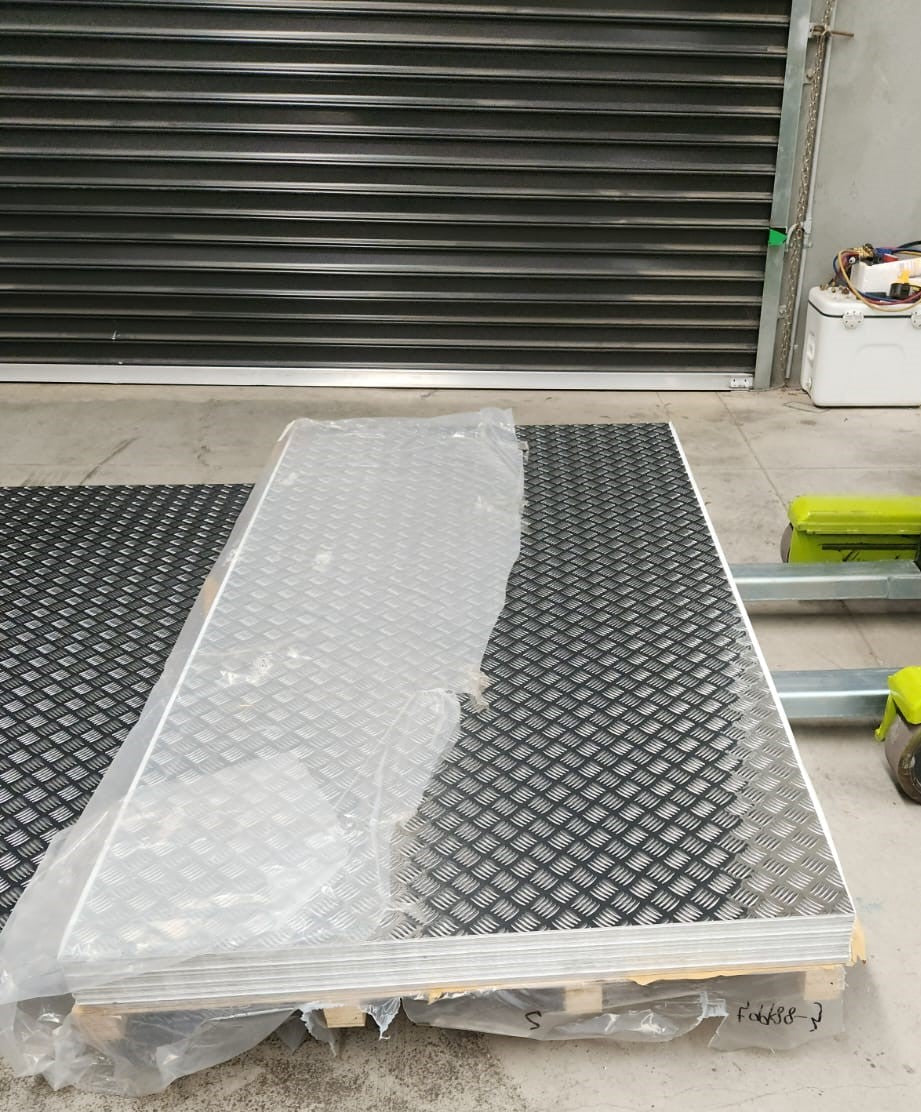 5052 Alloy Aluminium Checker Plate stored in a warehouse, showcasing its protective packaging and highlighting the detailed checkered design.